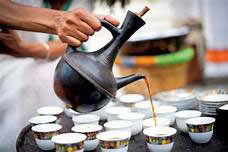 Yirgachefe coffee being served into small, gold banded cups